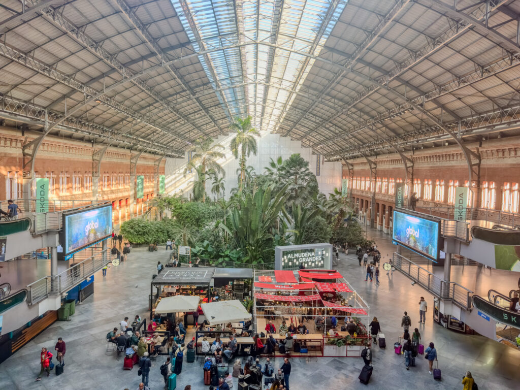 interior view from upper balcony of Atocha station in madrid spain with a palm garden and vendors