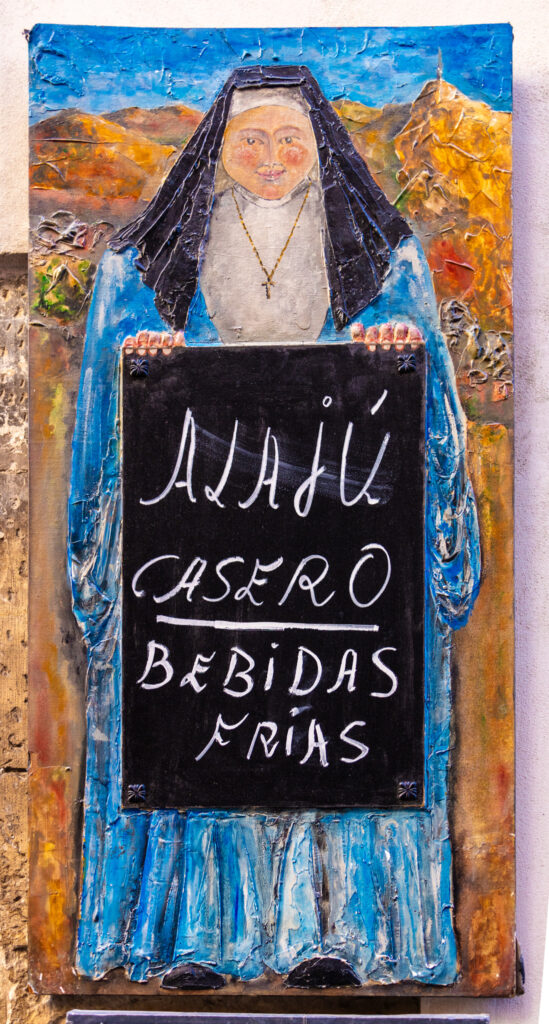 painted sign with nun holding sign for alajú and cold drinks for sale in Cuenca spain