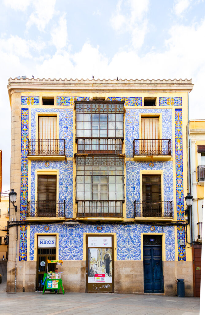 blue and yellow tiled building plaza San Juan caceres spain