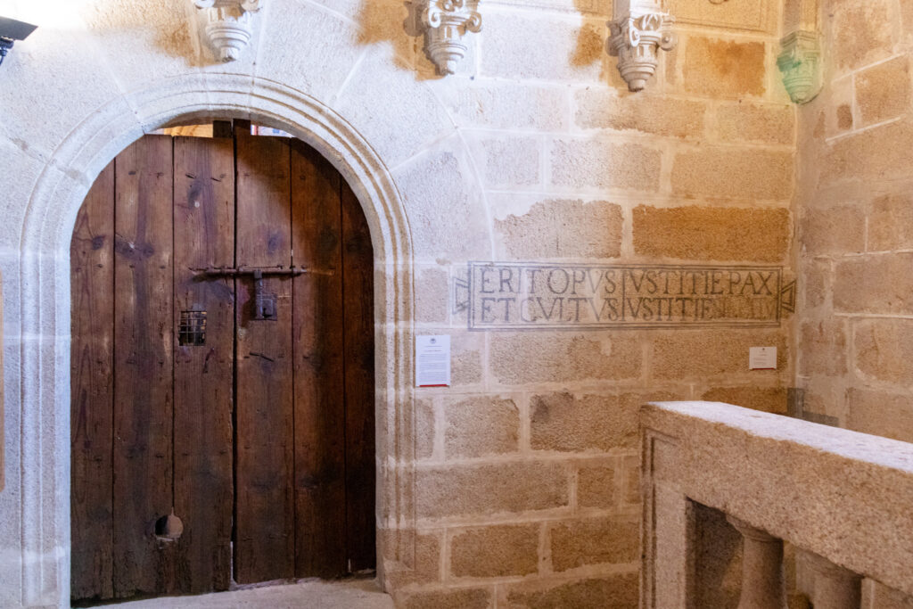 wooden door and latin inscription on wall in caceres cathedral spain