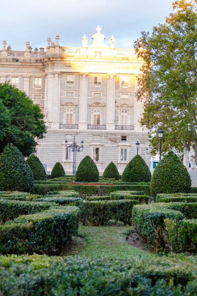 undulating bushes in the oriental garden and beam of sunlight on royal palace madrid