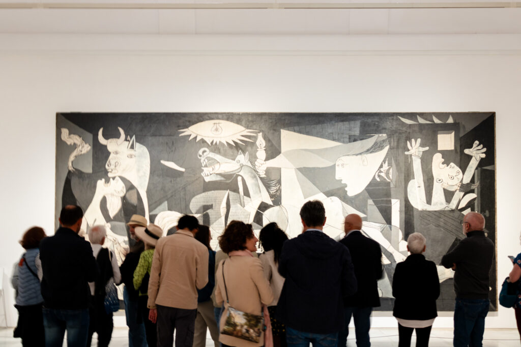 Picasso's guernica painting and people standing in front of it in Reina Sofia museum madrid