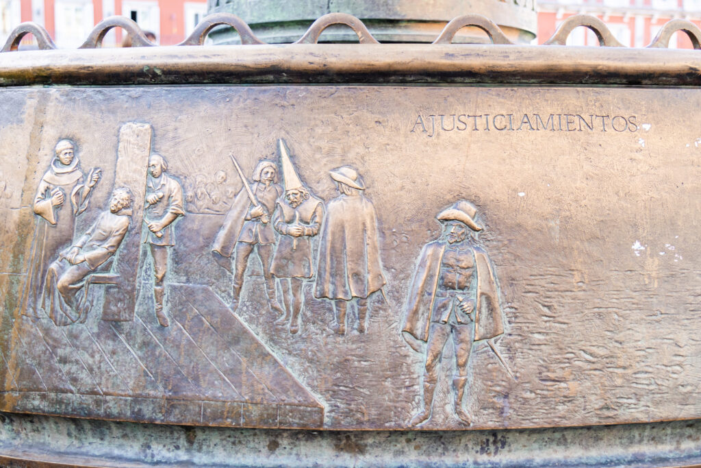 brass detail on bench of the Spanish inquisition and the word execution in Spanish