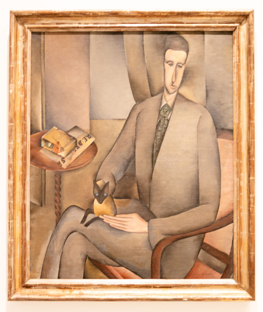 abstract painting on a man in a suit with a cat on his lap and books on a table next to him at Reina Sofia museum madrid