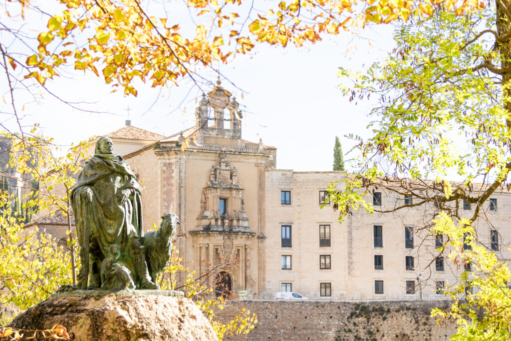 statue of a man with the parador of Cuenca spain in the background