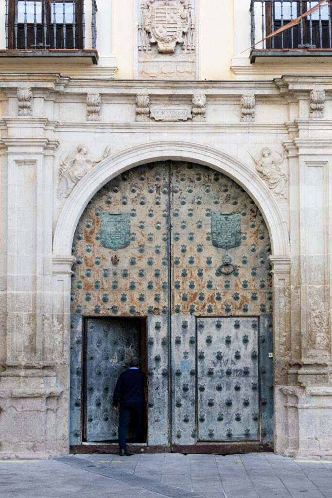 man entering old metal door in cuenca spain