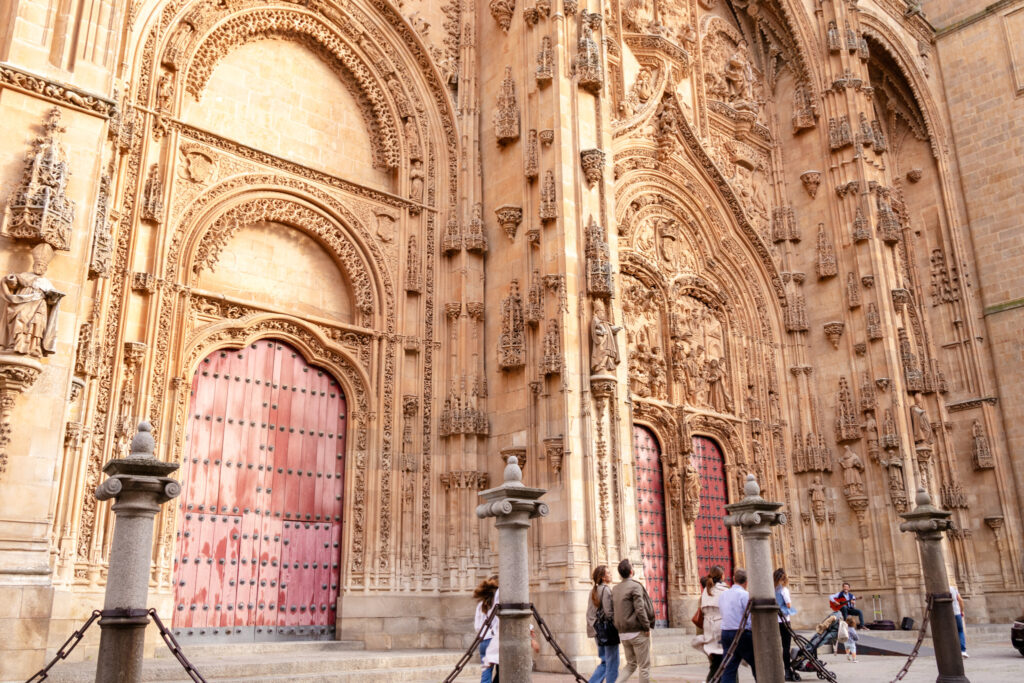 people walking in front of giant doors to Salamanca cathedral 