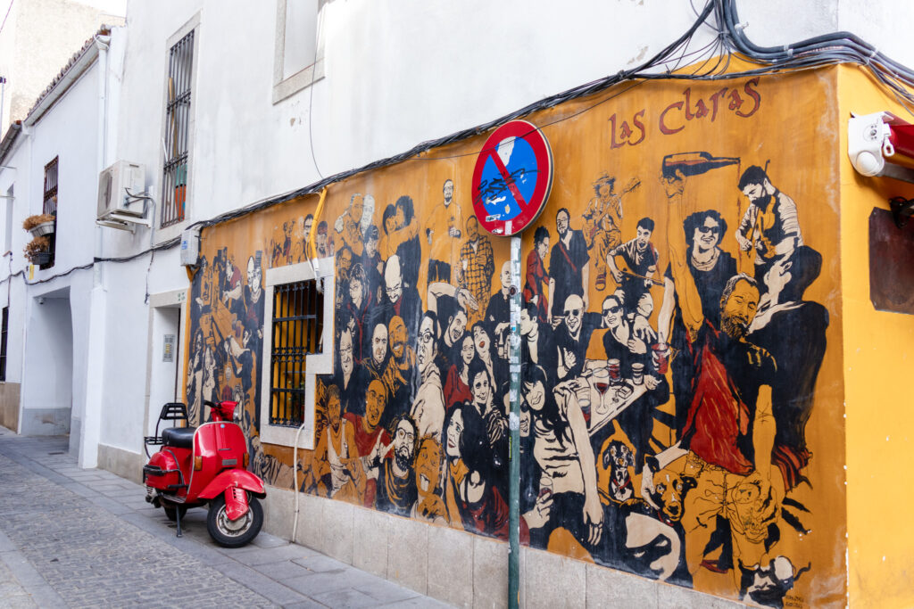 street art in caceres spain with yellow background and mostly black and white people having fun