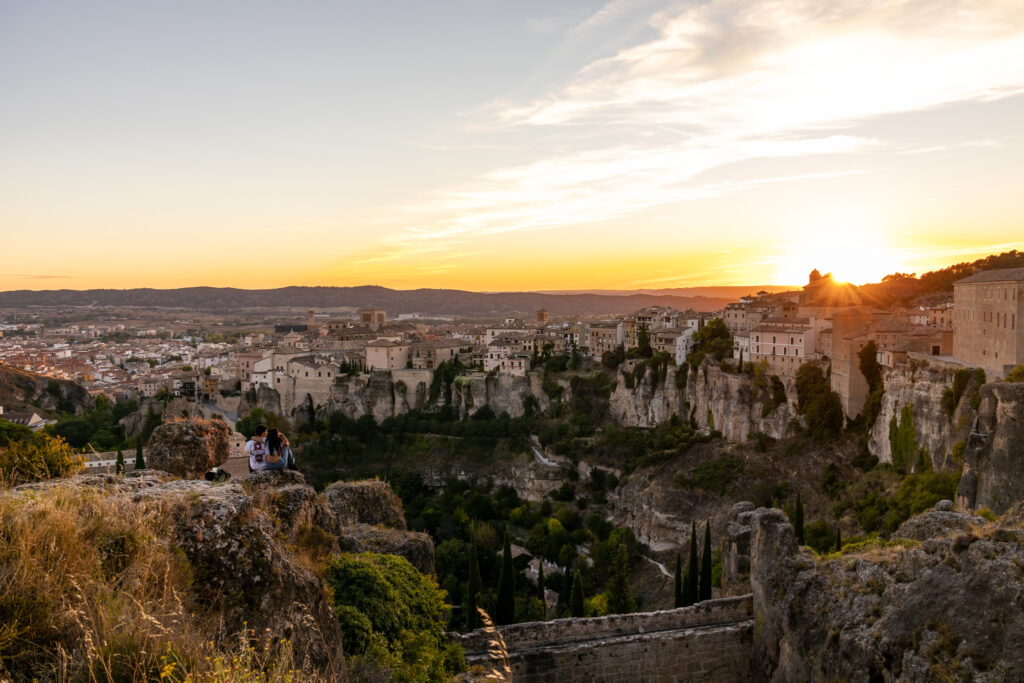 sunset over cuenca spain and couple sitting on rocks