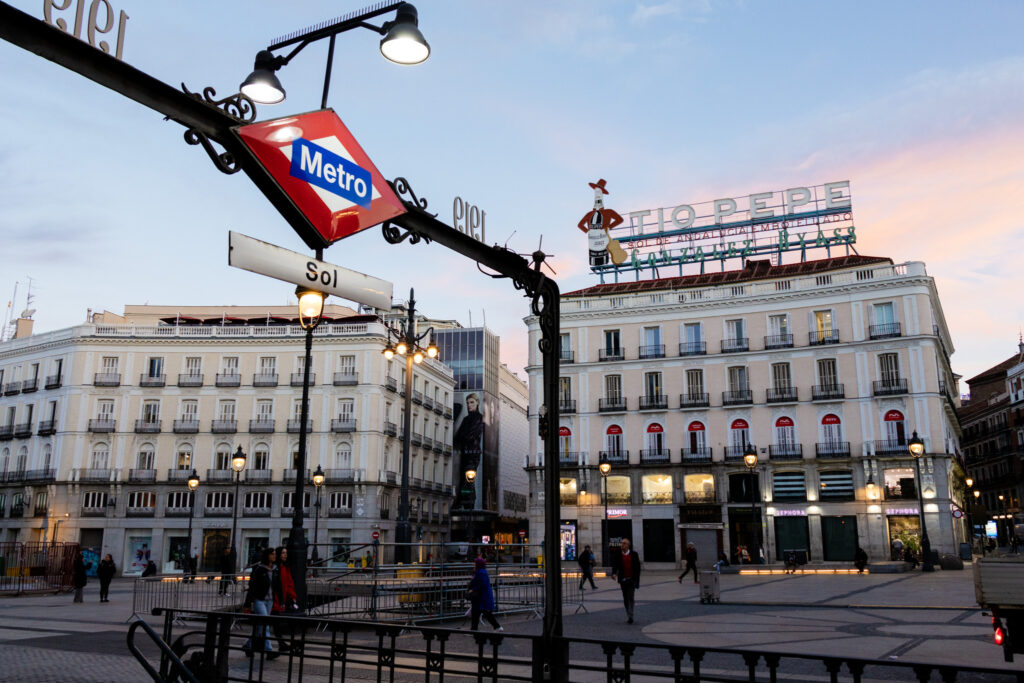 Sol metro station sign with the two Pepe sigh in the background in madrid