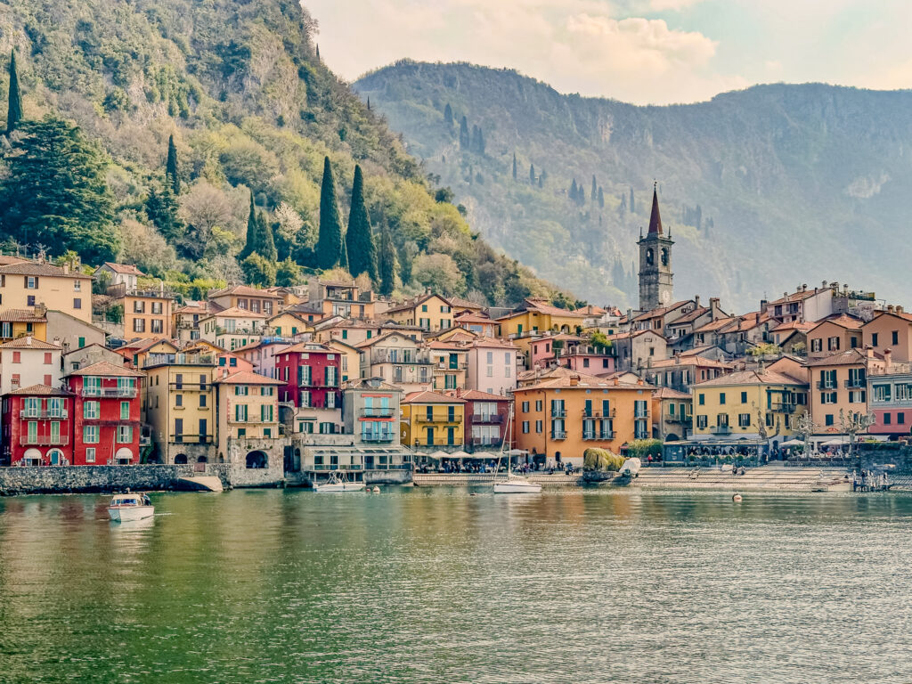 shore of Varenna italy lined with colorful buildings and mountains behind