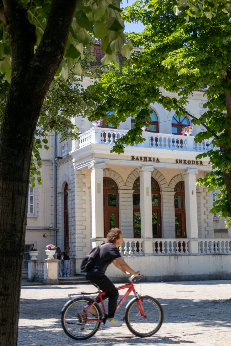 what to do in Shkodër a man rides a bike in front of Shkoder city hall